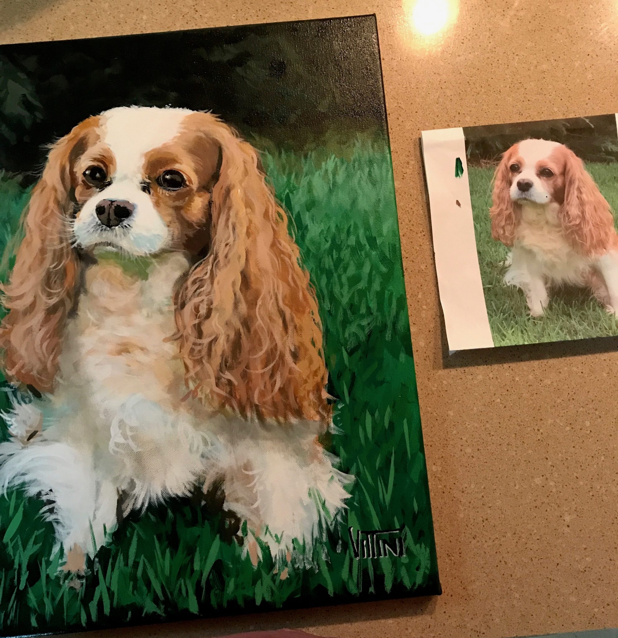 A Photograph of a dog sits next to a freshly painted portrait.
